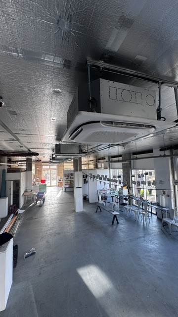 Ceiling-mounted air conditioning cassette above a large studio space