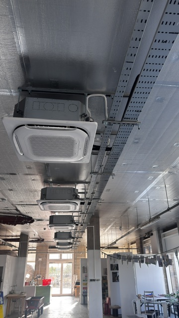 Row of ceiling cassette air conditioners along an exposed-services ceiling