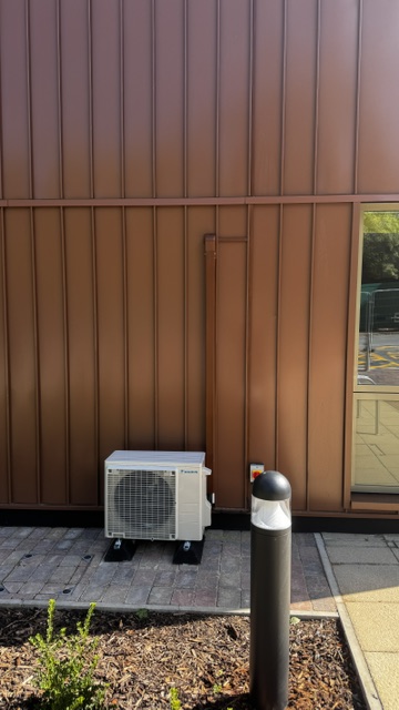 Outdoor air conditioning unit beside a pathway