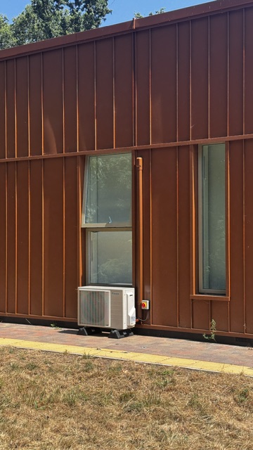 Air conditioning condenser at the base of a clad school wall