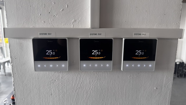 Three air conditioning zone controllers on a wall