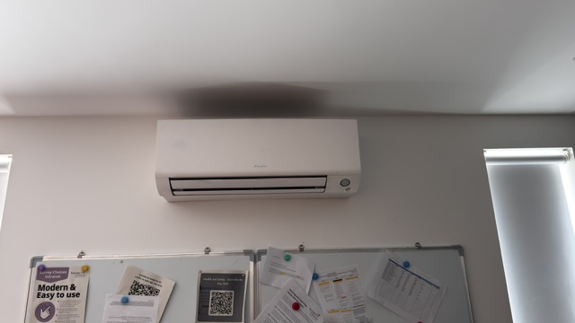 Wall-mounted air conditioner above a classroom noticeboard